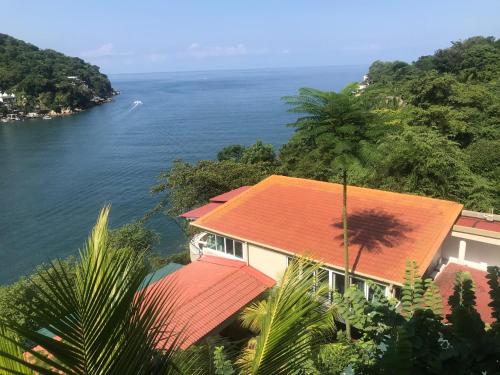 uma casa com um telhado vermelho ao lado da água em South Shore Villa Armonia Luxury Boutique em Puerto Vallarta