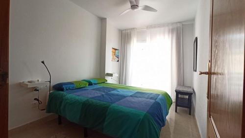 ein Schlafzimmer mit einem Bett mit einer blauen und grünen Decke in der Unterkunft Apartamento en Portmán in Portman