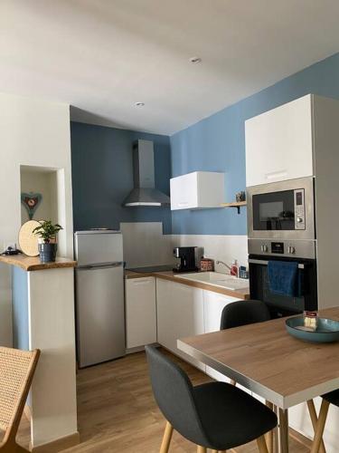 une cuisine avec une table et une cuisine aux murs bleus dans l'établissement Appartement cosy hyper centre, très tranquille, à Angers