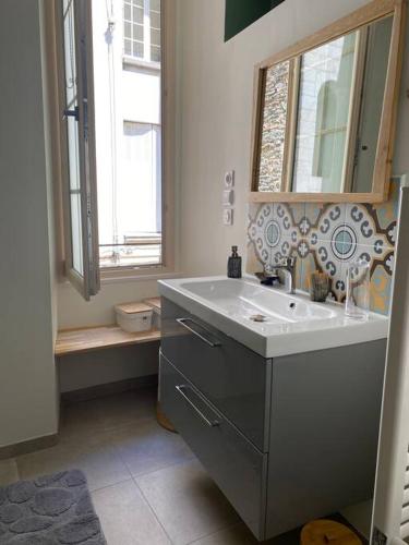 une salle de bain avec un lavabo, un miroir et une fenêtre dans l'établissement Appartement cosy hyper centre, très tranquille, à Angers