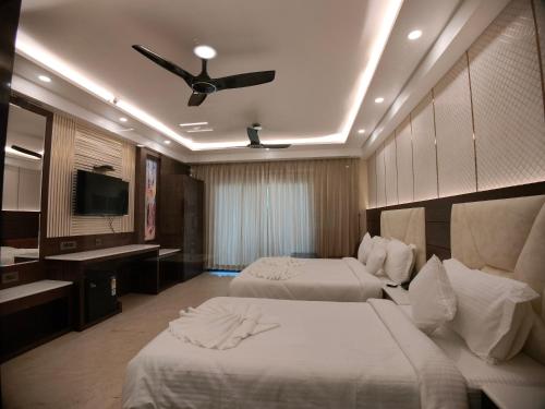 een hotelkamer met 2 bedden en een plafondventilator bij AGM GRAND HOTEL & Spa in Digha