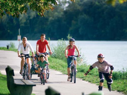 a group of people riding bikes down a path near a lake at Stadthotel Schärding in Schärding