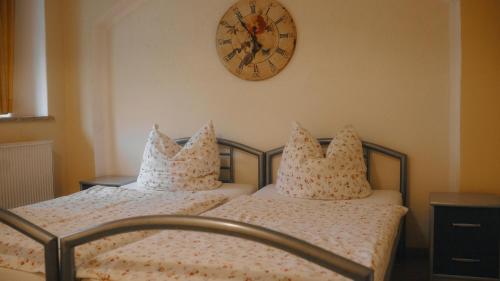 2 Betten in einem Schlafzimmer mit einer Uhr an der Wand in der Unterkunft Sylvias Ferienwohnung Nr.4 (Souterrain) in Görlitz