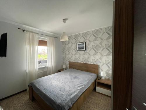 Schlafzimmer mit einem Bett und einem Fenster in der Unterkunft Apartament Ogrody in Kołobrzeg