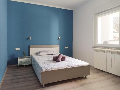 a bedroom with a bed with a blue wall at Apartment D&J 2 in Mošćenička Draga