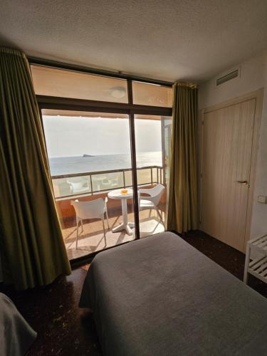 a room with a bed and a view of the ocean at Apartamentos Don Vicente in Benidorm