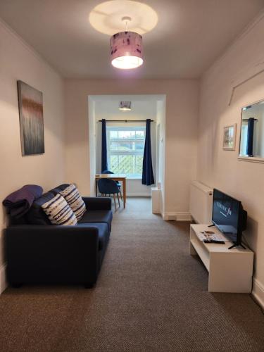 a living room with a couch and a tv at Rose Court Holiday Apartments in Torquay