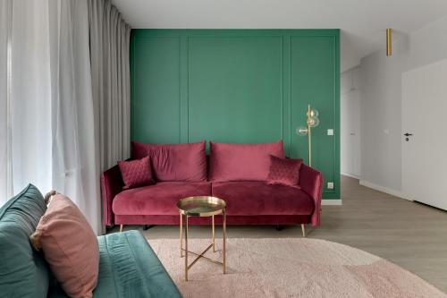 a living room with a red couch and a table at Lion Apartments - SCALA City Center Premium Apartments ID in Gdańsk