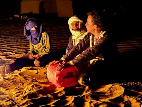 grupa ludzi siedzących na ziemi w obiekcie Adventure dans le desert w mieście Tagounite