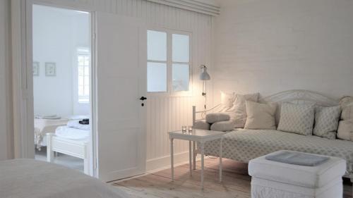 a white bedroom with a couch and a table at Store Ejlstrup Bed & Breakfast in Odense