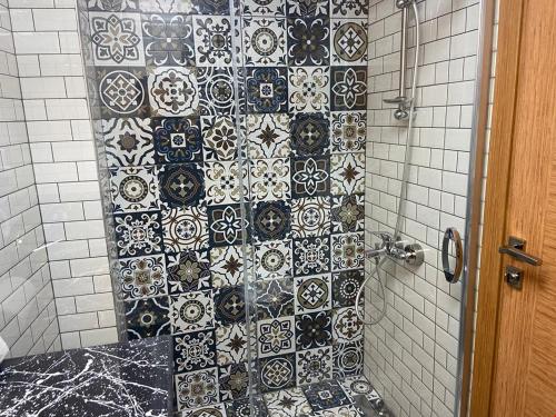 y baño con ducha y azulejos blancos y negros. en Renk Otel Karşıyaka, en Karşıyaka