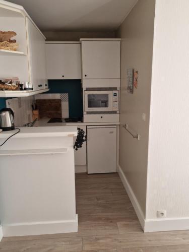 une cuisine avec des armoires blanches et un micro-ondes dans l'établissement Les voiles de la Baule, à La Baule