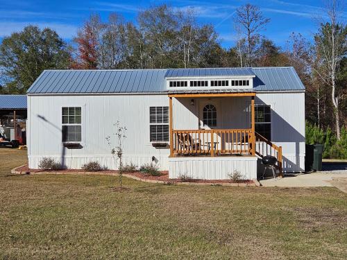 a white barn with a porch and a deck at Tiny home rentals near Ft Moore in Phenix City