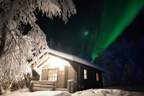 a cabin with the aurora in the sky at Muotkan Ruoktu Tunturikyla in Inari