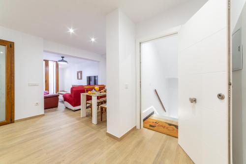 sala de estar con paredes blancas y sofá rojo en Casa Gómez, parking gratuito en Pleno Centro, en Almería
