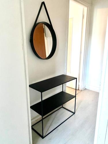 une étagère noire avec un miroir sur un mur dans l'établissement Appartement de 3 chambres, à Ris-Orangis