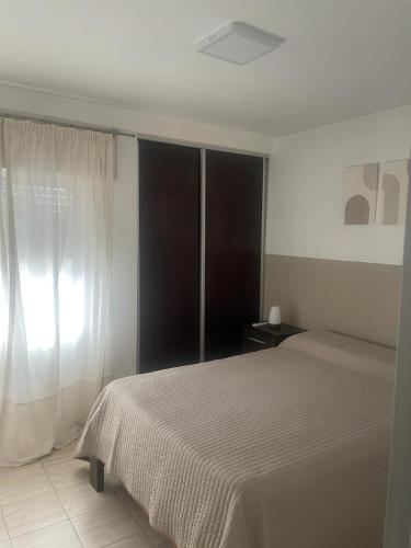 1 dormitorio con cama y ventana en Departamento macrocentro amueblado en Río Cuarto