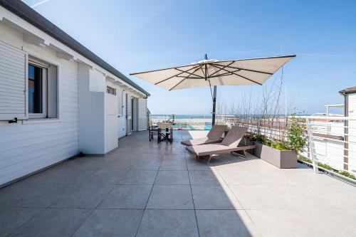 a patio with an umbrella and chairs on a balcony at Appartamento Luxury vista mare in Lido di Camaiore
