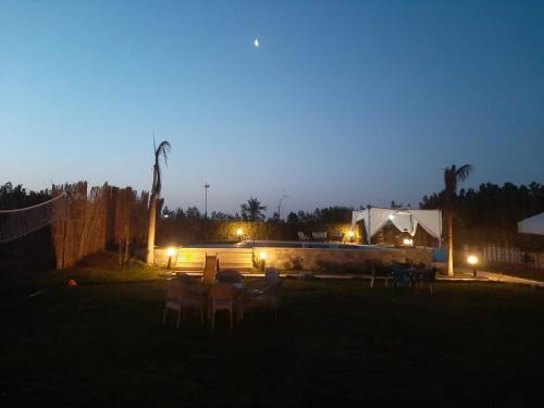 a group of tables and chairs in a yard at night at Dija's holiday rental in El-Qaṭṭa