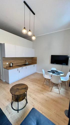 a living room with a table and a kitchen at Łokietkowo Apartamenty Szczecin Centrum in Szczecin