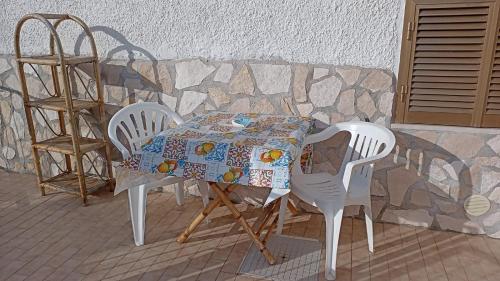 einen Tisch und zwei Stühle neben einer Wand in der Unterkunft Country House Gaeta in Gaeta
