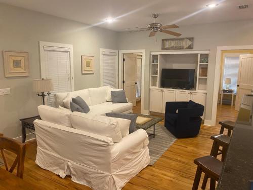 a living room with white furniture and a flat screen tv at Beach Bungalow, 3 Min Walk to Beach, Golf Cart, 4 bikes, Wagon in Seacrest