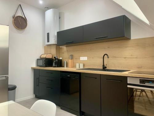 a kitchen with black cabinets and a sink at Appartement Cosy, Résidence de l’Ecluse in Arques
