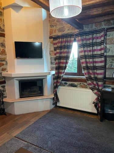 a living room with a television and a fireplace at Gioras Hotel in Palaios Agios Athanasios