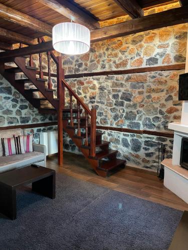 a living room with a staircase and a stone wall at Gioras Hotel in Palaios Agios Athanasios