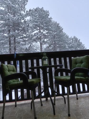 two chairs and a table on a balcony with snow at Simic Apartmani Tara in Kaludjerske Bare