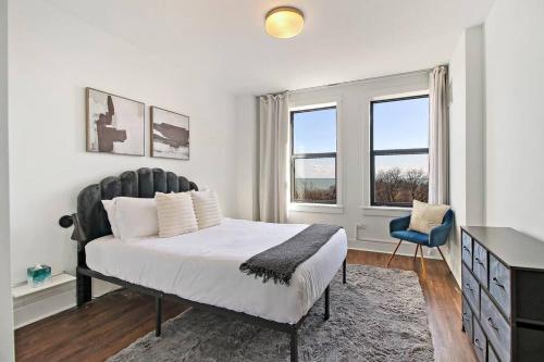 a bedroom with a bed and a desk and two windows at Chic & Elite 1BR Apartment in Hyde Park - Shoreland 714 in Chicago