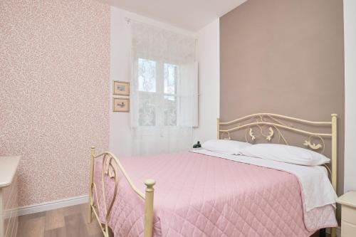Antica Casa del Segretario في Serramonacesca: غرفة نوم مع سرير مع لحاف وردي ونافذة