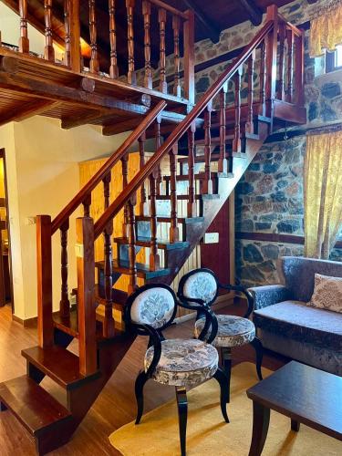 a living room with a staircase with two chairs at Gioras Hotel in Palaios Agios Athanasios