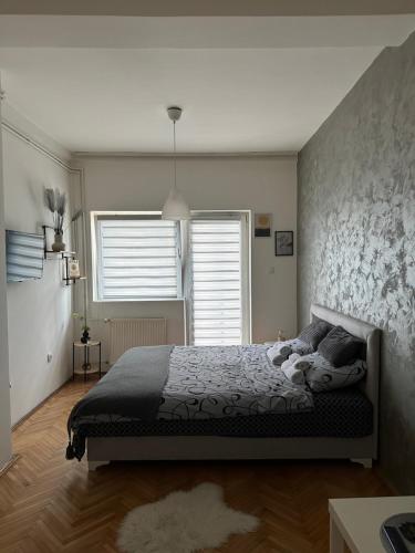 a bedroom with a bed and two windows at Loli apartman in Kraljevo