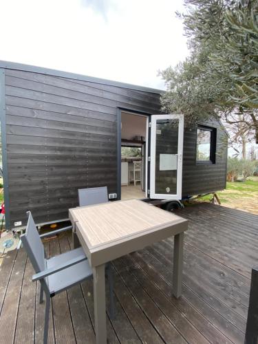 a tiny house with a table and chairs on a deck at Tiny house en pleine campagne in Arles