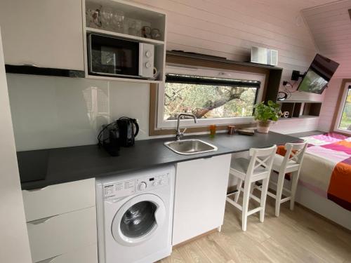 uma cozinha com uma máquina de lavar roupa numa pequena casa em Tiny house en pleine campagne em Arles