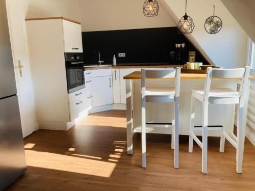 MoormerlandにあるFerienwohnung Wiekenblickの白いキャビネット、テーブルと椅子付きのキッチンが備わります。