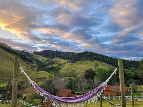 a purple hammock hanging on a fence in front of a hill at Pousada Vale Monte Azul in Santo Antônio do Pinhal