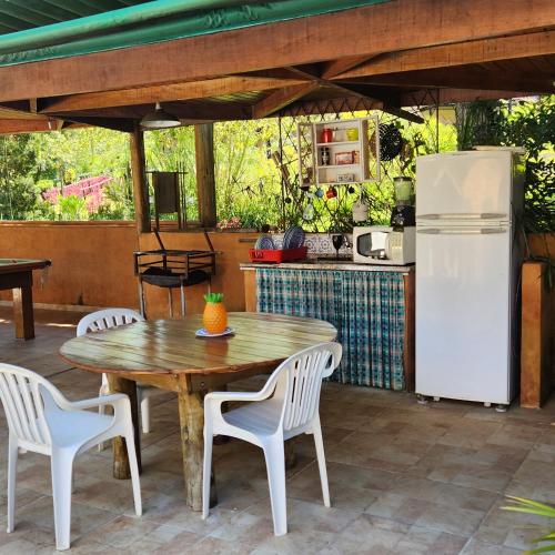 a patio with a table and chairs and a refrigerator at Pousada Vale Monte Azul in Santo Antônio do Pinhal