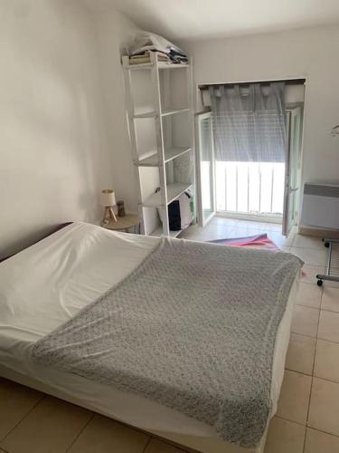 une chambre avec un lit et une étagère dans l'établissement Fabienne côté jardins de la fontaine, à Nîmes