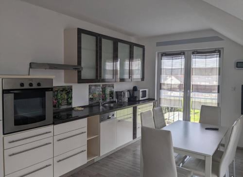 a kitchen with white cabinets and a table with chairs at Kempf Apartments in Rust