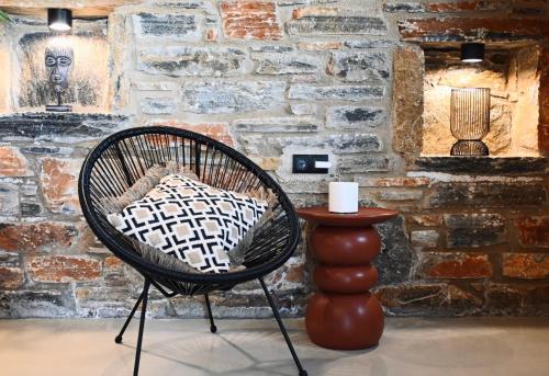 a chair and a table in front of a brick wall at Harmony Luxury Villas Naxos in Kastraki Naxou