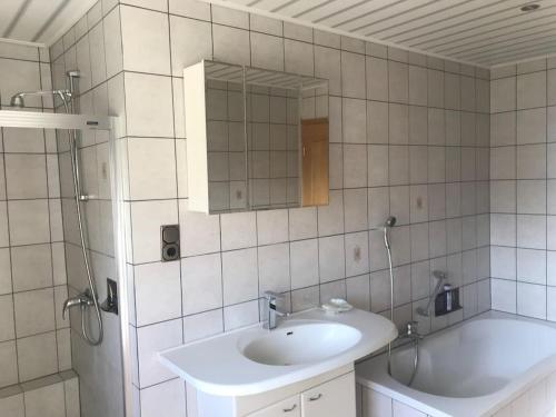 La salle de bains est pourvue d'un lavabo, d'un miroir et d'une baignoire. dans l'établissement Urlaub im Grünen - Ferienwohnung EG im Brunnenhof, à Reichshof 