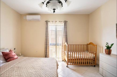a bedroom with a crib and a large window at Aurora Apartment in Żurrieq