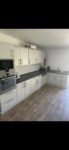 a large kitchen with white cabinets and a wooden floor at Ferienzimmer im schönen Eickhof in Warnow