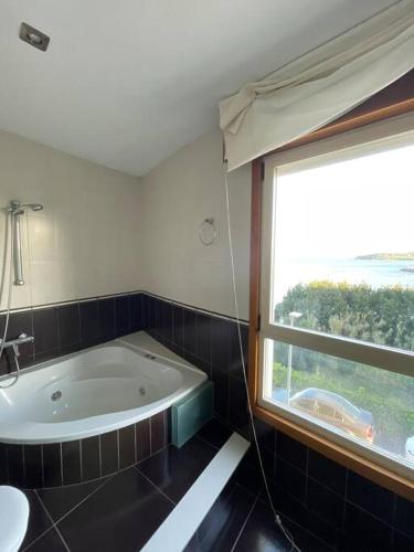 a bathroom with a bath tub and a window at Punta Salera house & beach in A Pobra do Caramiñal