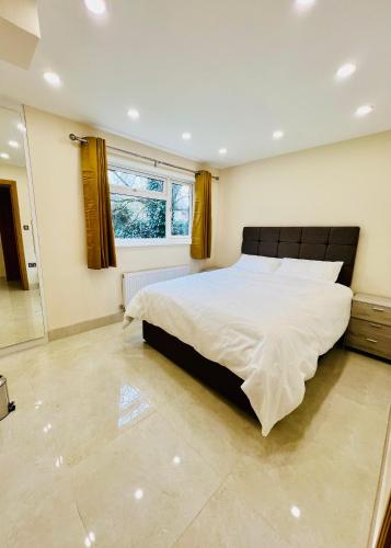a bedroom with a large bed and a window at 2 Bedroom Flat or Appartment near Heathrow with Garden in Uxbridge