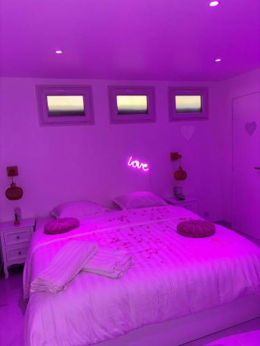 - une chambre violette avec un lit avec un signe d'amour au néon dans l'établissement Pinkroom06, à Nice