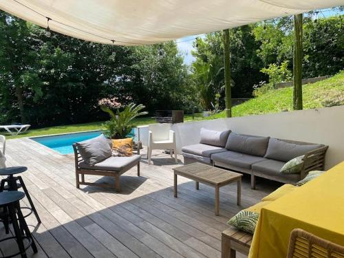 patio z kanapą, krzesłami i stołem w obiekcie Villa: Piscine, proche Centre & Mer w mieście Saint-Jean-de-Luz
