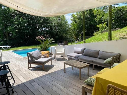d'une terrasse avec un canapé, des chaises et une table. dans l'établissement Villa: Piscine, proche Centre & Mer, à Saint-Jean-de-Luz